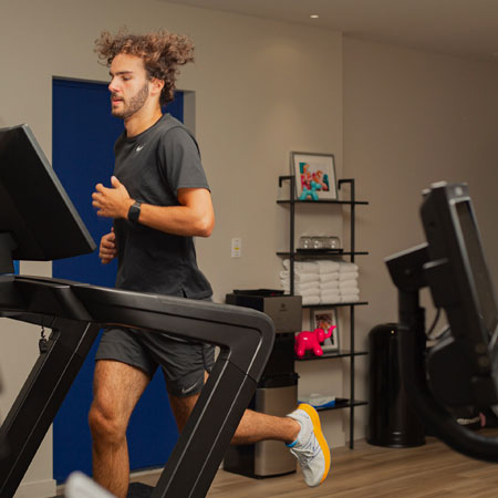 Guest running on a treadmill in the fitness room at Monsieur Jean