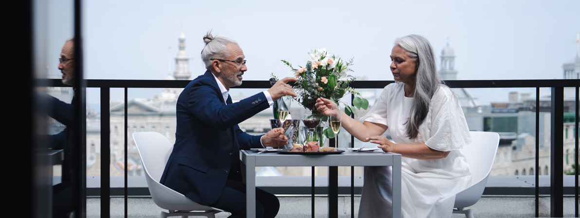 Couple profitant d’un repas sur une terrasse avec vue sur le Vieux-Québec et ambiance élégante