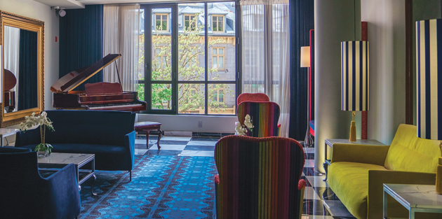Lobby design avec piano, fauteuils colorés et grande fenêtre lumineuse à l’Hôtel Monsieur Jean dans le Vieux-Québec