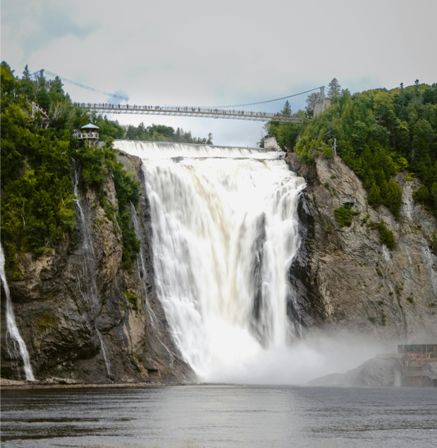 Vue des chutes Montmorency avec leur impressionnante cascade entourée de falaises boisées et un pont suspendu traversant le sommet.