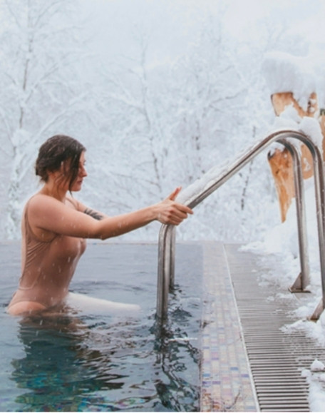 Outdoor Nordic bath in winter, steam rising from hot water, snow on the ground, Quebec City region spa
