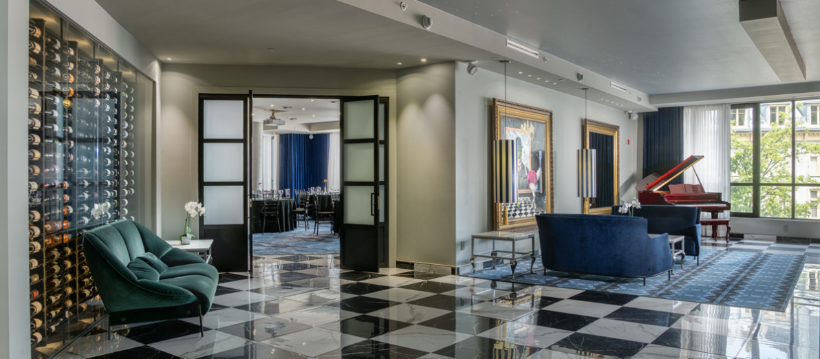 Piano lounge at Hôtel Monsieur Jean featuring a grand piano, glass wine cellar, contemporary seating, and access to event space in Old Québec.