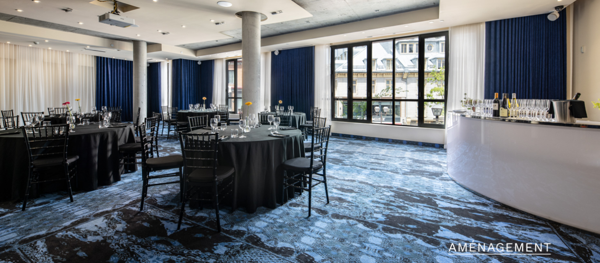 Salle de banquet avec tables rondes, bar intégré et grandes fenêtres à l'Hôtel Monsieur Jean dans le Vieux-Québec.