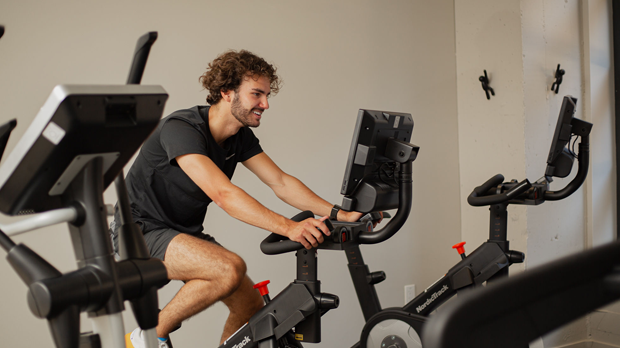 Client utilisant un vélo stationnaire dans la salle d'entraînement de l'hôtel Monsieur Jean, au cœur du Vieux-Québec.