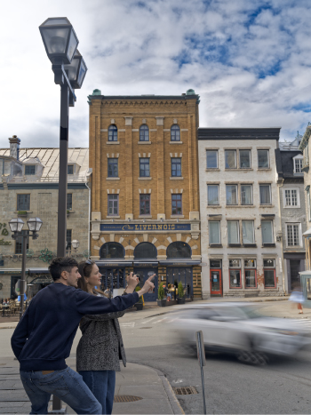 Explorer le Vieux-Québec à pied depuis Monsieur Jean Deux visiteurs prennent une photo devant les façades historiques du Vieux-Québec, à quelques pas de Monsieur Jean.